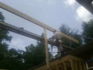 Carpenter setting a ridge beam over a new addition frame — Ice Dam Removal by Roofing Brothers in Taholah