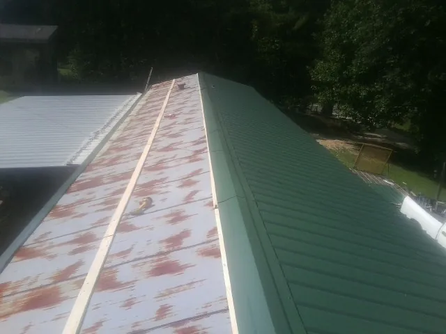 Old rusted panels beside newly installed green metal roofing — Wind Damage Roof Repair by Roofing Brothers in Taholah