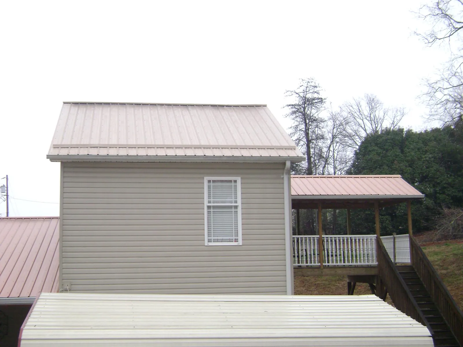 Tan metal roofs on a two story addition and attached porch, from a Roof Replacement job in Taholah