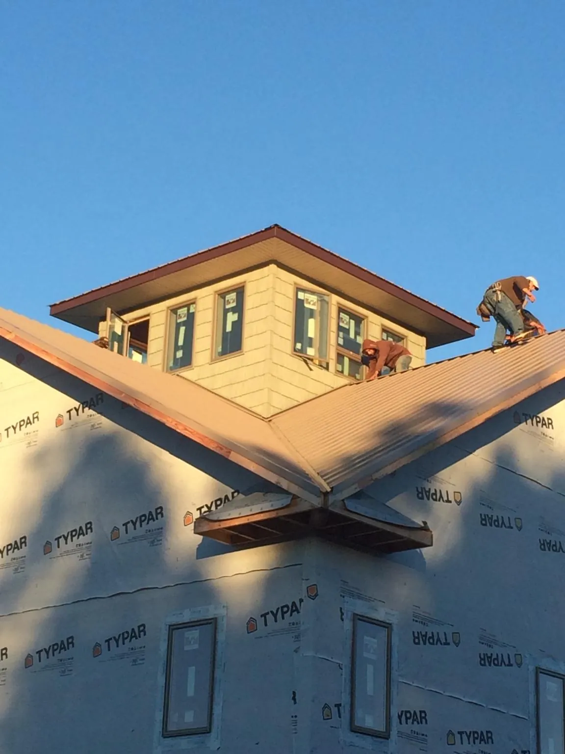 Roofers working around a rooftop cupola on a new metal roof at sunset — Roof Waterproofing in Taholah by Roofing Brothers